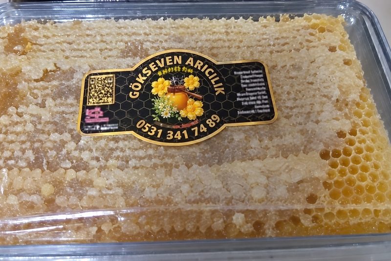 Ahşap tahta üzerinde, hücrelerinden bal süzülen bir dilim petek bal